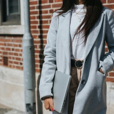 Crop ethnic freelancer with laptop on city street