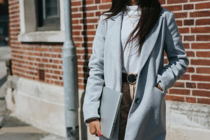 Crop ethnic freelancer with laptop on city street